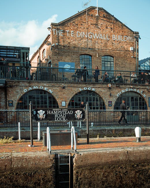 An exterior view of the historic Dingwall Building, a brick structure with large arched windows and a sign reading 'The Dingwall Building' at the top. In front, there is a metal railing and a sign for